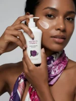 Model holding Yuvraani Kojic Acid 1% and Mulberry Body Lotion with cream applied on the face for body pigmentation, uneven skin tone and dark spots.